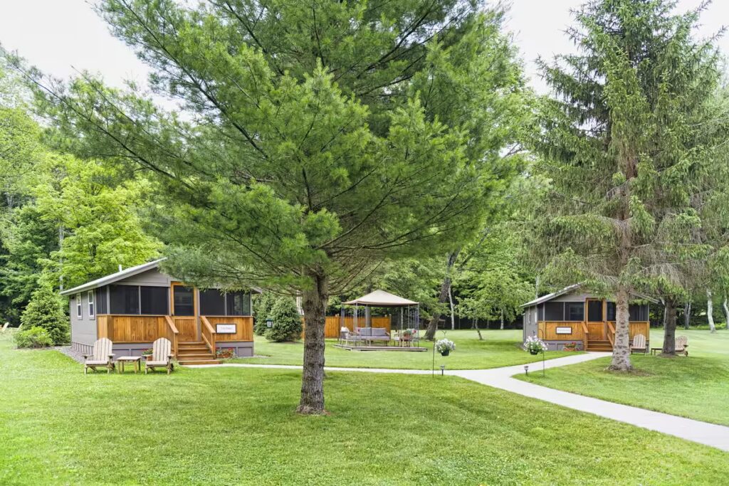 Cozy Catskills cabin accommodation surrounded by lush greenery in spring season, with blooming flowers and clear skies.