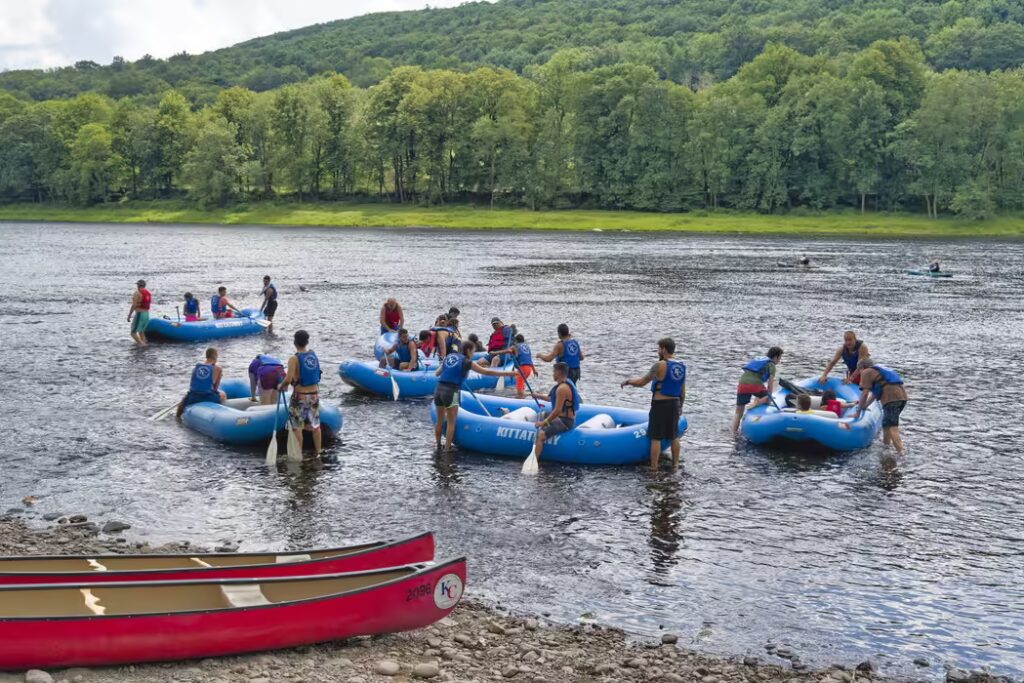 Families enjoying an exciting river rafting adventure in the Catskills, surrounded by lush green mountains and clear water.